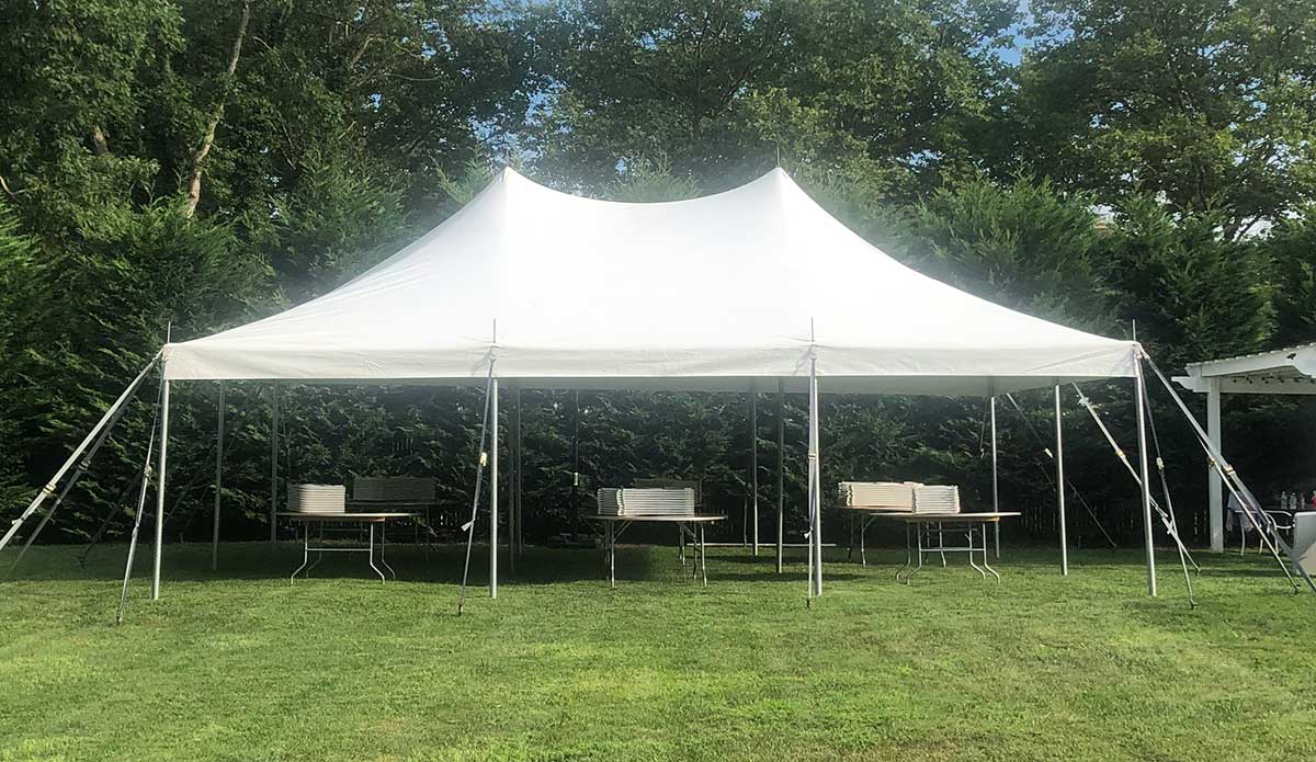 White high peak tent with tables set up on a lawn