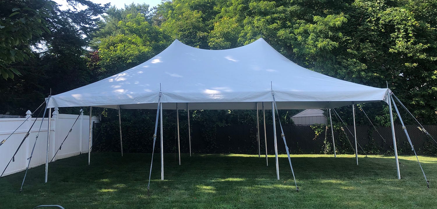 White party tent set up on a lawn with trees behind it